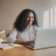Imagem de uma mulher sorrindo e mexendo no computador para simbolizar como liderar uma equipe