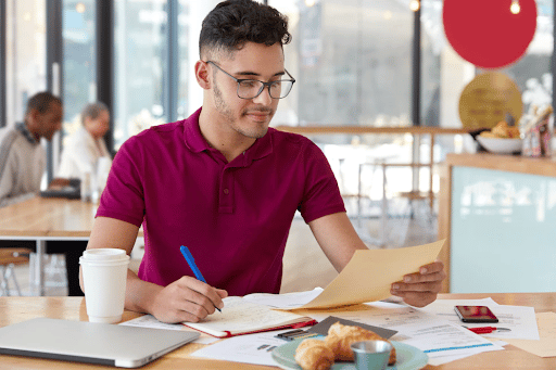 Imagem de um homem de óculos com uma caneta e um papel nas mãos para simbolizar diferença entre estágio e jovem aprendiz