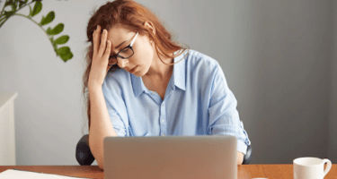 Imagem de uma mulher na frente do notebook com expressão de cansaço para simbolizar o que é quiet quitting