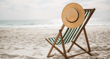 Imagem de uma cadeira, com um chapéu pendurado na praia, para simbolizar aviso de férias coletivas
