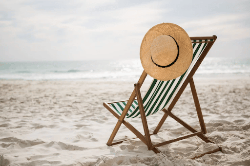 Imagem de uma cadeira, com um chapéu pendurado na praia, para simbolizar aviso de férias coletivas