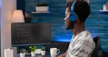 Imagem de um homem mexendo em um computador com fone de ouvido para simbolizar as profissões em alta em 2023