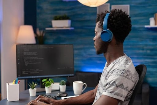 Imagem de um homem mexendo em um computador com fone de ouvido para simbolizar as profissões em alta em 2023