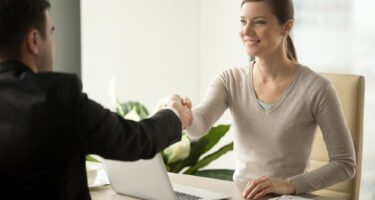 Imagem de uma mulher dando um aperto de mãos em um homem para simbolizar a recontratação de funcionário