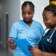 Imagem de duas enfermeiras olhando para um papel para simbolizar a jornada 12 por 36